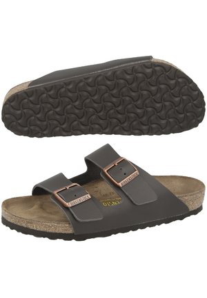 Sandales marron avec deux sangles ajustables, semelle en liège et semelle en caoutchouc texturé présentant un motif en vagues. Accentué par du matériel en cuivre.
