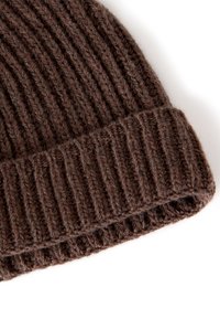 Brown knitted beanie with ribbed texture and folded cuff. Made from thick yarn, featuring uneven stitching and a soft, warm finish.