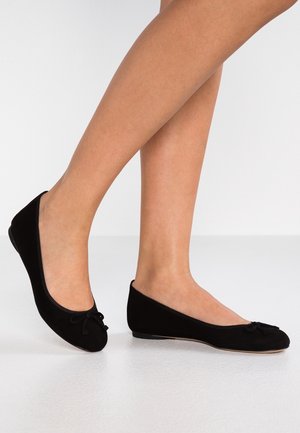 Sorte balletflade med en blød fløjlslignende tekstur, rund tå og en lille sløjfeaccent på forsiden. Lav profil og enkelt design.