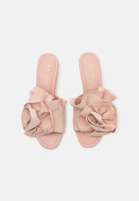 Sandale roz, tip slip-on, cu un upper texturat, prezentând o mare floare din material moale. Talpă netedă și branding subtil în aur.