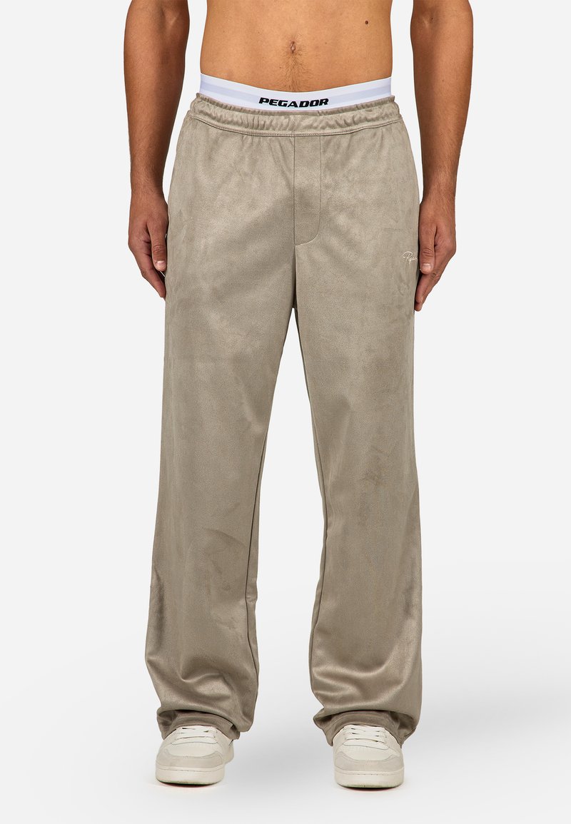 Light beige sweatpants made of soft material. Features an elastic waistband with "PEGADOR" logo, side pockets, and a relaxed fit.