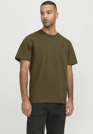 Camiseta de cuello redondo verde oliva de algodón suave con mangas cortas. Presenta un pequeño logo rojo en el pecho. Corte recto. Ajuste casual.