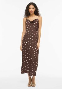 Rjavo maxi obleka s pikami, z vratnim izrezom v obliki rute in tankimi naramnicami, izdelana iz gladkega blaga, z bež pikami in ravnim krojem.