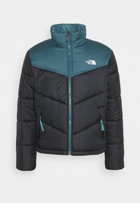 Giacca imbottita con una parte superiore color teal e una parte inferiore nera, chiusura con zip e tasche laterali con accenti teal.