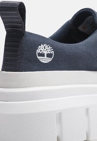 Námořnická plátěná teniska s bílou texturovanou podrážkou, na patě s bílým logem stromu a poutkem pro snadné nazouvání a zouvání.