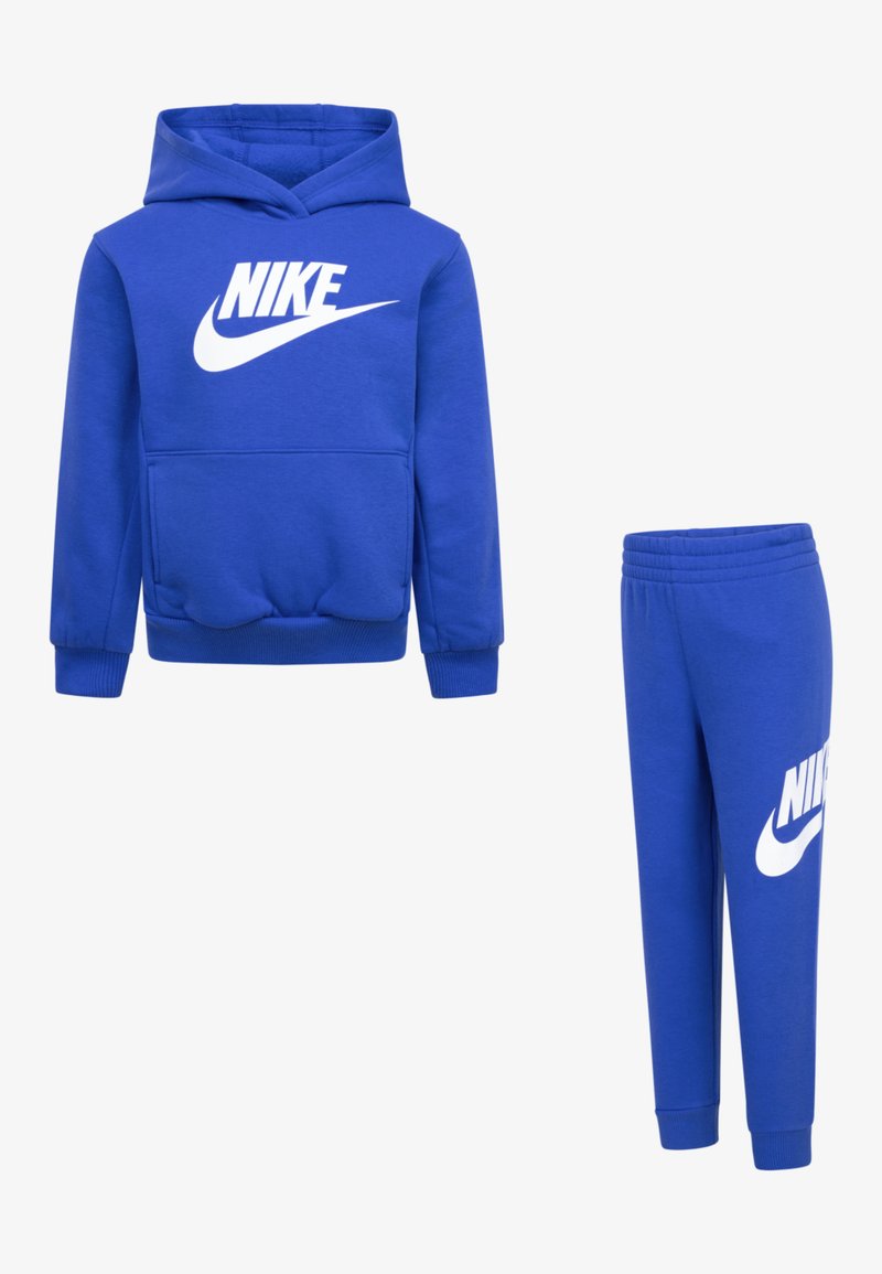 Zila kapuce un sporta bikses komplekts, izgatavots no kokvilnas maisījuma. Kapucei ir priekšējā kabata un liels balts Nike logs; biksēm ir logo uz kājas.