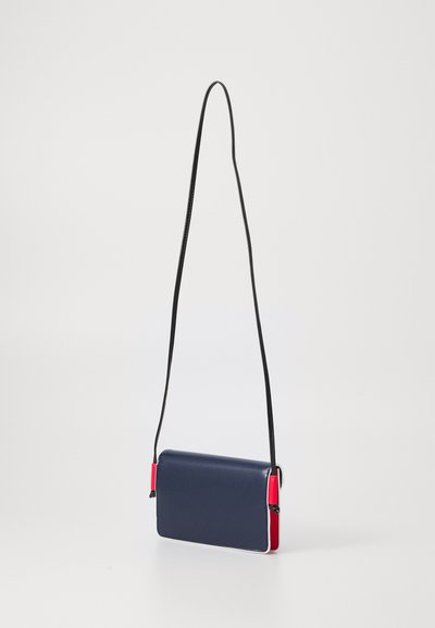Borsa a tracolla blu navale con accenti rossi, forma rettangolare, texture lucida e tracolla sottile nera. Presenta cuciture a contrasto e hardware minimale.