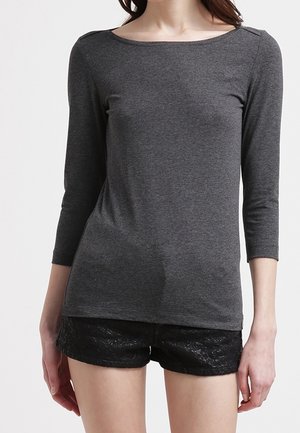 Grijs topje met lange mouwen en een afgeronde halslijn met schouderdetails, gecombineerd met zwarte kanten shorts, met een gladde textuur.