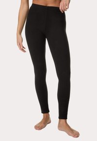 Zwarte leggings van een gladde, rekbare stof. Kenmerken zijn een hoge tailleband en een getailleerd silhouet, dat naar de enkels uitloopt.