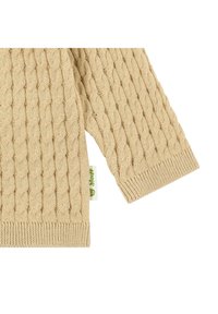 Béžový pletený svetr s texturovaným vzorem typu kabel, se žebrovanými manžetami. Obsahuje zelenou značkovou etiketu připevněnou na boku.