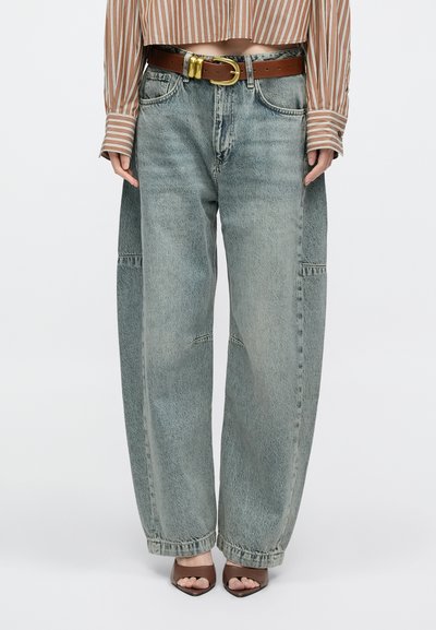 Heledad sinise tooniga laiad teksapüksid, valmistatud denimist, kahel ees taskul, õmbluse detailidega ja kõrge vöökohaga, kombineeritud pruuni nahkvöö ja kontsakingadega.