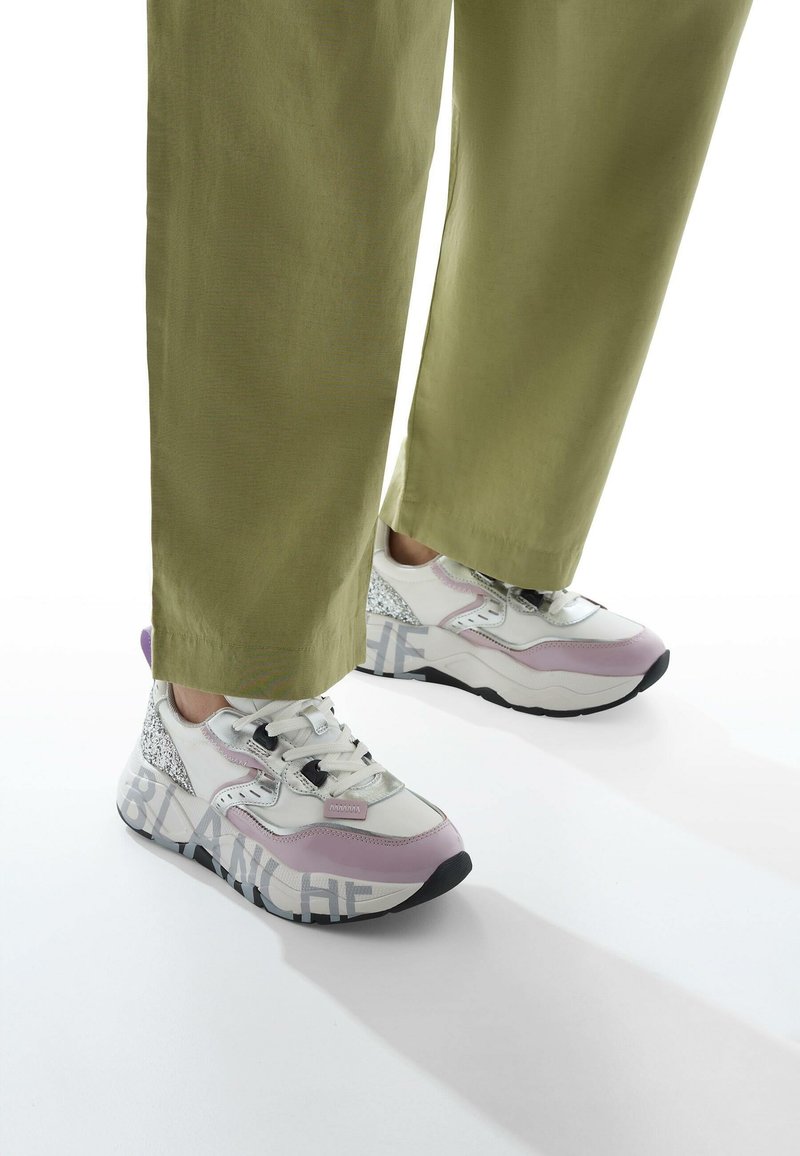 Sneakers in white, lavender, and silver with textured accents and a chunky sole. Light laces and the word "BLANCHE" printed on the side.