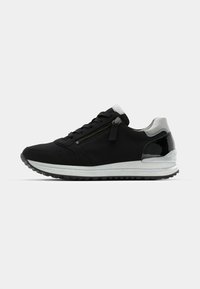 Black athletic shoes featuring a smooth fabric upper, silver accents, a side zipper, and a thick white midsole with a textured black outsole.