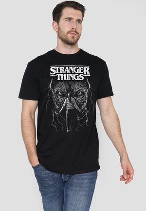 Black cotton t-shirt featuring a graphic print of a character from "Stranger Things" with lightning details, crew neck, and short sleeves.