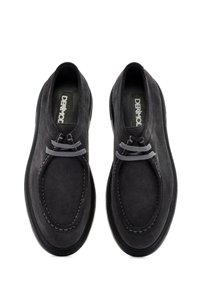 Zwarte suède schoenen met een ronde neus, voorzien van grijze veters en stiksels, een platte zwarte zool en een eenvoudig, gestroomlijnd ontwerp.
