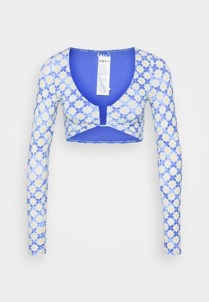 Top corto a maniche lunghe blu con un motivo floreale caratterizzato da fiori gialli e bianchi, realizzato in un tessuto elastico e leggero.