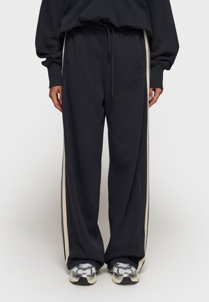 Pantaloni sportivi navy con vestibilità rilassata, vita con cordino e strisce crema laterali; realizzati in tessuto morbido e presentano un delicato dettaglio del logo.