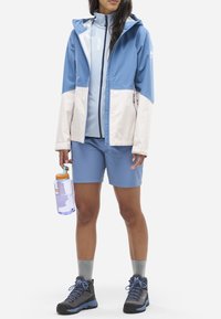 Hellblaues Outdoor-Jackett mit weißen Akzenten, kombiniert mit passenden Shorts. Verfügt über ein Reißverschluss-Design und ist mit einer Wasserflasche ausgestattet.