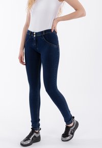 Jeans ajustados de denim azul oscuro con una textura suave, que cuentan con un cierre de doble botón, bolsillos delanteros y costuras en contraste.