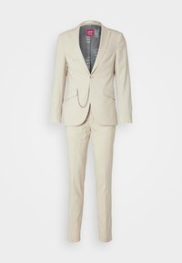 Beige pak met een blazer met één knoop en puntige revers, zijzakken en bijpassende flat-front broek met een strakke, op maat gemaakte pasvorm.