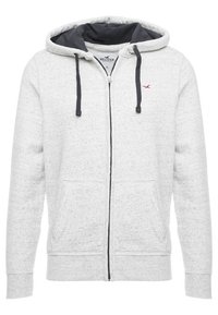 Sudadera con cremallera de color gris claro hecha de tela texturizada, con un forro azul marino, dos bolsillos frontales y un pequeño logotipo rojo en el pecho.
