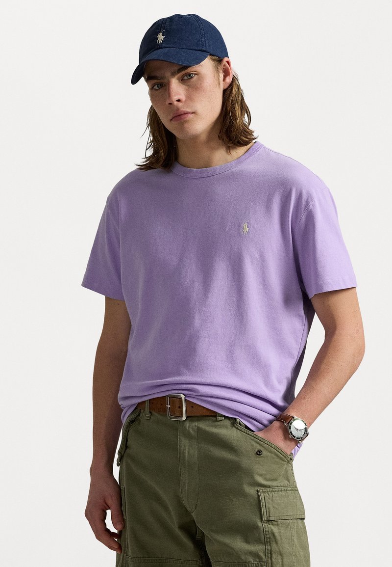 Lavendel färgad bomull T-shirt med rund halsringning och en liten broderad logotyp. Matcher med olivgröna cargo shorts och ett brunt bälte.