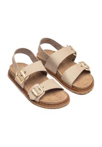 Sandalias de cuero beige con dos correas anchas, acentos de hebilla dorada y una plantilla texturizada. Presentan una suela de goma marrón gruesa con puntos.