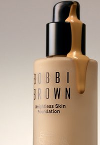 Bobbi Brown Weightless Skin Foundation i en frostet glassflaske, beigem liquid som strømmer fra en svart pumpe, med fet svart skrift.