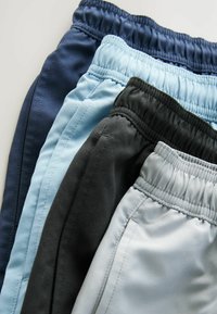 Quatre paires de shorts de sport en marine, bleu clair, noir et gris clair. Chacun a une taille élastique et un tissu lisse avec un design simple.