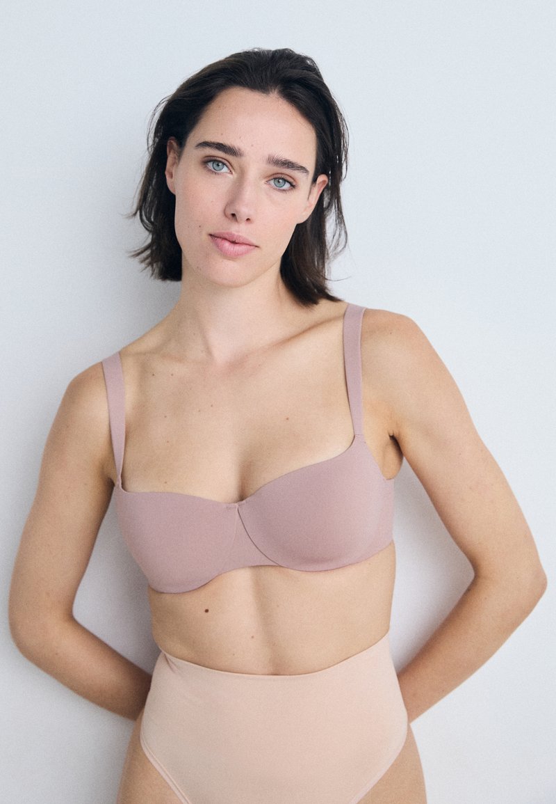 Lys rosa bh med glatt tekstur, underwire-støtte og justerbare stropper, kombinert med høyt liv kjøttfarget truse.
