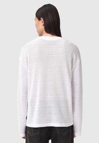 Hvid letvægts striktrøje med teksturerede vandrette striber, afslappet pasform, lav skuldersøm og rund halsudskæring.