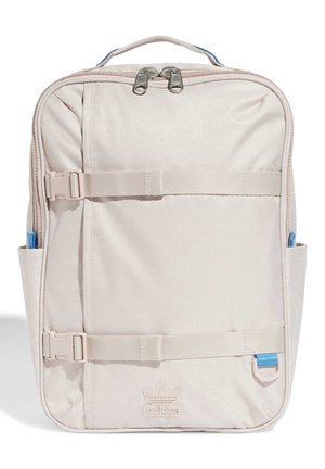 Mochila rectangular Adidas de color beige claro con doble cremallera, dos correas horizontales con hebilla, bolsillos laterales, asa y logo delante.