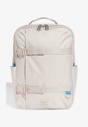 Mochila rectangular Adidas de color beige claro con doble cremallera, dos correas horizontales con hebilla, bolsillos laterales, asa y logo delante.