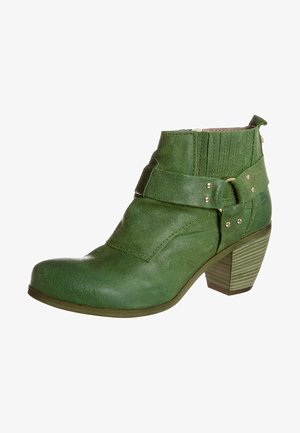Botte de cheville en cuir vert avec une finition texturée, des détails de bandes superposées et un talon bloc. Présente des accents dorés et une fermeture éclair sur le côté.