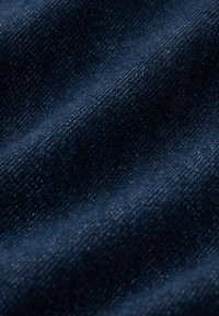Donkerblauwe denimstof met een licht gestructureerd oppervlak, die een rijke weving en subtiele variaties in kleur en dikte toont.