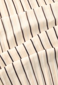 Tissu léger avec une base crème, présentant des rayures verticales marron et noires. La texture semble douce et lisse avec une légère transparence.