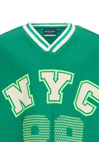 Zielona bawełniana koszulka z dekoltem w serek, kontrastującymi białymi paskami, oversize'owym napisem "NYC" oraz kropkowanym wzorem z "99" w jasnej zieleni.