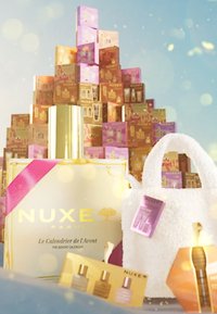 Kalendarz adwentowy NUXE w złotym opakowaniu, różowa wstążka, biała puszysta torba oraz kolorowe pudełka z produktami w ułożeniu jednym na drugim.