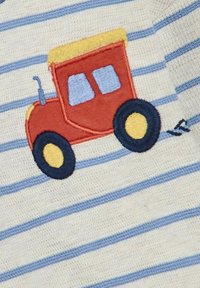 Wyszywany czerwony traktor na tkaninie w kolorze kremowym i jasnoniebieskim w paski, z żółtymi kołami i żółtym dachem kabiny.