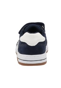 Marineblaue Wildleder-Sneaker mit weißem Lederakzent an der Ferse, Gummisohle und klassischem Low-Top-Design. Klettverschluss für einfaches An- und Ausziehen.