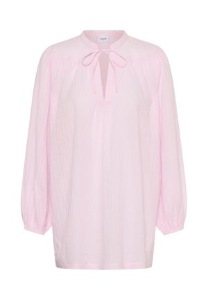 Blouse rose clair à manches longues avec poignets froncés, col rond et nœud papillon à l'avant au-dessus d'une encolure en forme de goutte.
