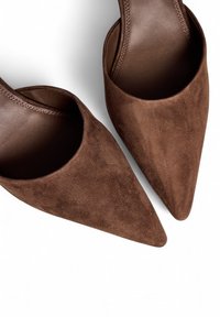 Mules en daim marron à bout pointu avec un intérieur en cuir lisse et une silhouette épurée, conçus pour un enfilage facile.