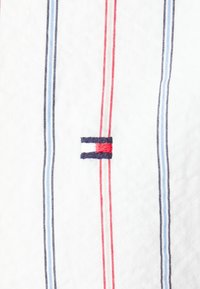 Tessuto a righe bianche, con linee rosse, blu e navy. Logo ricamato in evidenza in blu, bianco e rosso. Texture morbida.