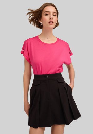 Fuchsia korte mouwen t-shirt met een ronde hals en mouwdetails, gecombineerd met een zwarte geplisseerde rok met zijzakken.