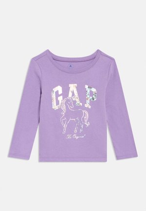 T-shirt à manches longues lilas pour enfant avec des lettres GAP brillantes et un dessin de licorne centré sur le devant.