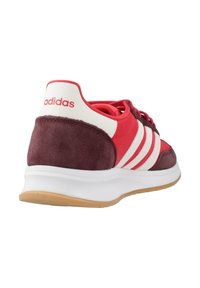 Crvene i tamnoljubičaste atletske cipele od antilopa i sintetičkih materijala, s bijelim prugama i gumeni potplat. Na leđima se nalazi Adidas logo.