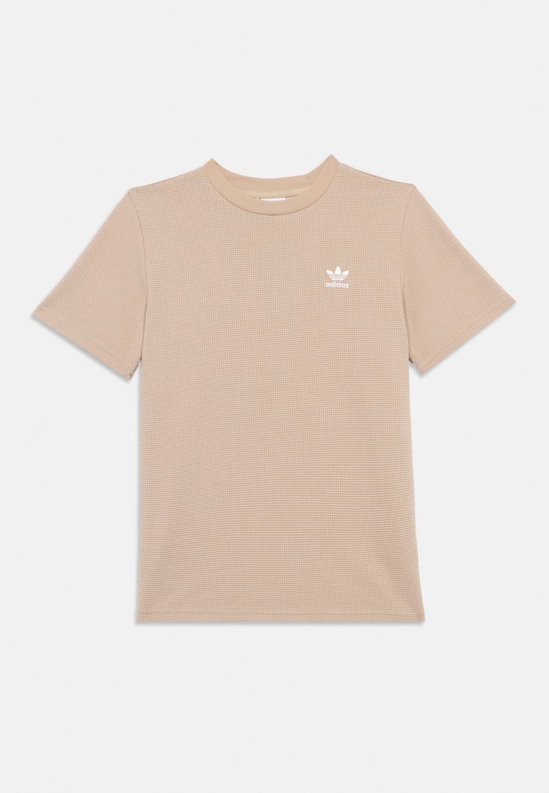 Béžové tričko s krátkym rukávom vyrobené z textúrovaného materiálu, s rebrovaným dizajnom a bielym logom na ľavej hrudi.