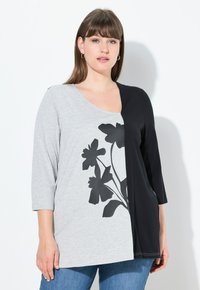 Top grigio e nero con maniche a tre quarti, presenta una stampa floreale nera sul lato grigio e un lato nero uniforme. Tessuto morbido.