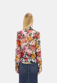 Blusa con stampa floreale in tessuto leggero e trasparente con rose rosa, rosse e gialle, maniche lunghe e polsi con bottoni.