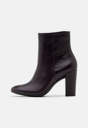 Ciemnobordowe skórzane botki za kostkę o eleganckim designie, zaokrąglonym nosku i masywnym, kwadratowym obcasie. Gładka faktura z minimalnymi detalami.